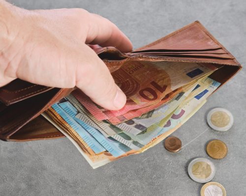 Senior man holds a wallet with euro banknotes in his hand, euro banknotes in the wallet. Wallet with money in a man's hand, background idea of paying taxes, buying or paying for services